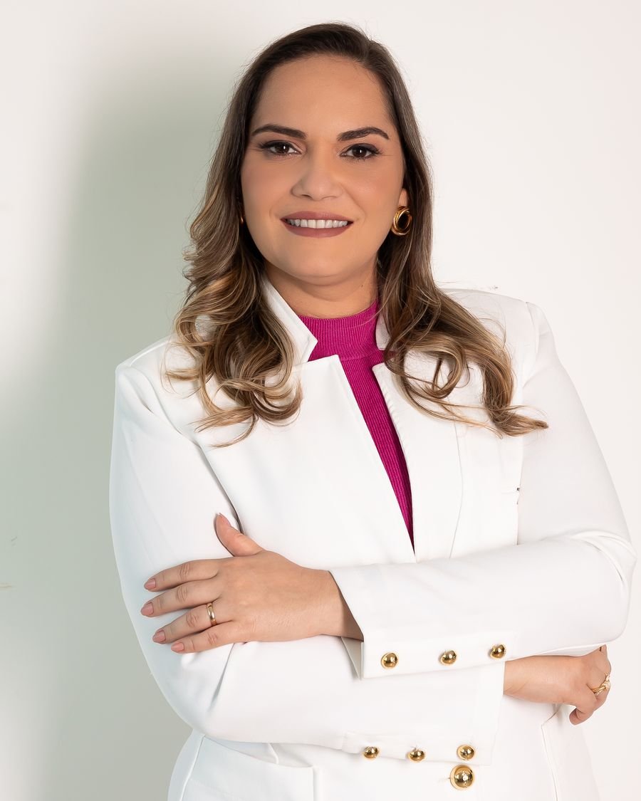 Dra. Adriana Britto de jaleco branco, com os braços cruzados